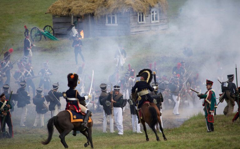 Horse mounted officers and soldiers with rifles and muskets fighting on field in countryside during reenactment of Napoleonic war