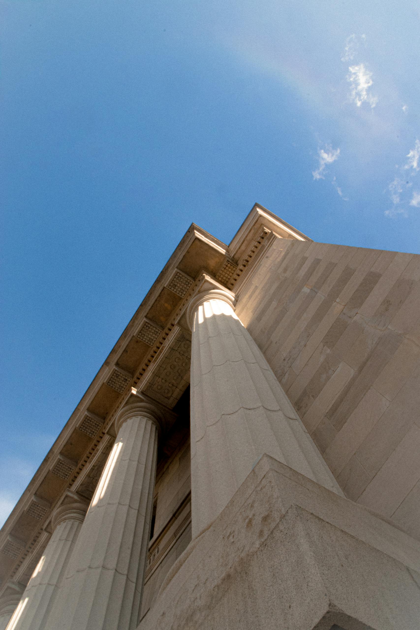 Low angle view of classical columns against a bright blue sky, highlighting architectural elegance.